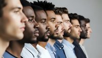 Diverse group of professional men in business attire standing in profile line formation against neutral background for corporate teamwork concepts.