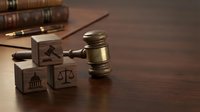 Wooden gavel with legal symbol blocks on desk representing justice system, law firm services, attorney consultation, and judicial proceedings.