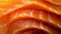 Fresh raw salmon slices arranged in layers showing vibrant orange color and marbled texture, macro food photography for culinary and restaurant use.