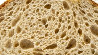 Closeup of sliced bread crumb texture with air pockets and holes, suitable for food photography, baking, and culinary design projects.
