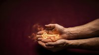 Male hands cupping glowing golden key with warm light rays on dark burgundy background symbolizing protection, security and opportunity.
