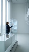 Professional businesswoman interacting with futuristic holographic display in modern white office interior with large windows and minimalist design.