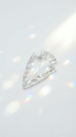 Clear quartz crystal arrowhead on white background with rainbow light reflections creating magical spiritual energy for healing meditation and wellness practices.