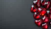 Shiny red glass heart shapes scattered on dark background creating romantic corner composition. Elegant Valentine's Day or love concept design element.
