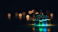 Laboratory glass vials with colorful chemical solutions glowing under dramatic lighting against dark background with bokeh lights for research.