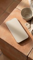 Smartphone with blank white screen on terracotta clay surface with ceramic pottery cup and natural textures for mockup design and branding projects.
