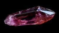 Raw pink tourmaline crystal specimen with natural geometric facets and translucent properties isolated on black background, displaying rich magenta hues and light reflections.