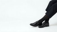 Professional businessman legs in black dress shoes and dark suit pants walking forward on white background for business and corporate design concepts.