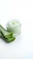 Natural aloe vera skincare cream in glass jar with fresh cut aloe leaves on white background for organic beauty and wellness products.