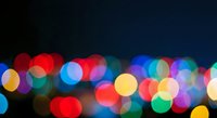 Colorful bokeh lights creating dreamy atmosphere with soft focus circles in red blue green yellow colors against dark background for festive designs.