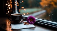 Steaming coffee cup with purple gerbera daisy on notebook near window with bokeh lights creating cozy autumn atmosphere, morning relaxation concept.