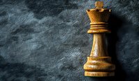 Wooden queen chess piece standing against dark textured background with dramatic side lighting, showcasing strategy and leadership concepts in business and gaming.