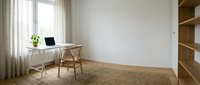 Minimalist home office with wooden desk, chair and shelving unit in bright room with natural light and neutral decor for modern workspace design.