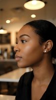 Young African American businesswoman in profile view at modern office cafe with warm lighting and contemporary interior design for professional workplace concepts.