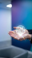 Hands holding glowing eco globe icon with leaves symbolizing environmental protection and sustainable business practices in modern office setting.
