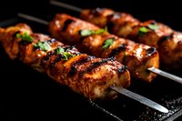Grilled chicken skewers with caramelized glaze and fresh herbs on metal sticks against dark background, close up view showing juicy meat texture and char marks.