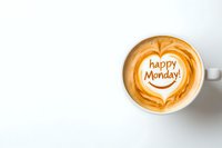 Latte art coffee cup with happy Monday text written in foam on white background, heart-shaped cappuccino design for social media and greeting posts.