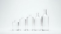Clear glass bottles of various sizes arranged in row on white background, empty containers for packaging, cosmetics, beverages, laboratory use.