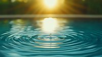 Single water drop creating concentric ripples on turquoise water surface at sunset, with golden sun reflection and bokeh effect, capturing tranquil nature moment.