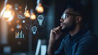 Young African American businessman contemplating innovative ideas with glowing light bulb icons and business analytics graphics floating in dark office space.