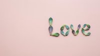 Succulent leaves arranged to spell the word Love on a soft pink background, minimal flat lay composition for Valentine's Day or wedding design.