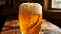 Chilled golden beer with thick foam head and condensation in pint glass, carbonated beverage for pub, bar, restaurant, and beverage industry marketing.