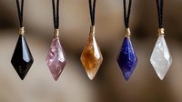 Crystal pendants on black cord necklaces featuring natural gemstones in black, pink, amber, blue and clear quartz arranged in row against blurred background.