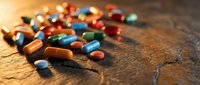 Colorful pharmaceutical pills and capsules scattered on wooden surface with warm sunlight creating medical healthcare concept for treatment and medication.