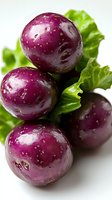 Fresh purple radishes with water drops on green lettuce leaves against white background, macro food photography showing vibrant colors and texture.