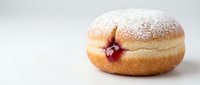 Freshly baked round pastry dusted with powdered sugar, filled with red jam, isolated on white background for bakery and food design projects.