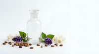 Natural skincare serum bottle with elderberry extract, coffee beans and white flowers on clean background for cosmetic product photography.