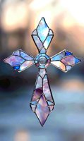 Stained glass cross with iridescent blue and pink panels, crystal centerpiece catching light against soft bokeh background. Religious art for church decor.