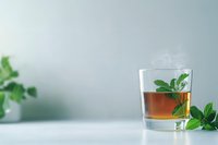 Glass of whiskey or bourbon garnished with fresh mint leaves on light background, minimalist cocktail composition with copy space for beverage menu.