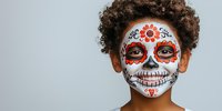 Traditional Day of the Dead sugar skull face paint makeup with red floral design on white base, featuring detailed patterns and artistic celebration motif on gray background.