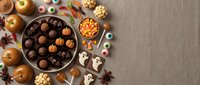 Halloween chocolate treats and candies with pumpkins, spooky sweets, autumn desserts flat lay on brown background for seasonal celebrations.