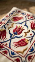 Traditional Ottoman Turkish embroidery with red tulips and blue floral motifs on cream fabric showcasing intricate needlework and cultural heritage craftsmanship.
