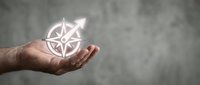 Hand holding glowing compass symbol for navigation guidance and direction finding in business strategy and life choices.