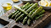 Fresh green asparagus spears with olive oil, sea salt and lemon on rustic wooden cutting board. Healthy organic vegetable cooking ingredient for spring recipes.