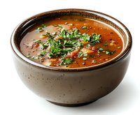 Hot tomato soup garnished with fresh parsley and black pepper served in rustic brown ceramic bowl against white background, ready for food service.