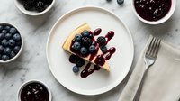 Delicious crepe topped with fresh blueberries and blackberries drizzled with berry sauce on white plate, healthy breakfast dessert meal concept.