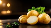 Fresh raw potatoes with parsley leaves on dark rustic wooden surface against blurred warm lights background, one potato cut in half showing white flesh.