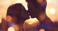 Romantic couple silhouettes about to kiss at golden hour sunset with warm bokeh lights creating intimate atmosphere for love and relationship concepts.