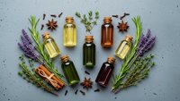 Essential oils collection with lavender, rosemary and herbs arranged on textured surface for aromatherapy and natural wellness treatments.