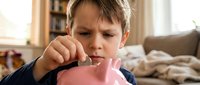 Young boy with light skin tone and brown hair brushing teeth with pink toothbrush indoors. Dental hygiene and children's oral care concept for healthcare and wellness content.