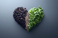 Heart shape made from black beans, sunflower seeds and fresh microgreens on dark background, creative healthy food composition for nutrition blogs.