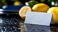 Fresh lemons with blank white card on dark granite surface. Mockup template for culinary branding, restaurant menus, recipe cards or food marketing materials.