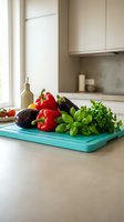 Fresh vegetables and herbs on turquoise cutting board in modern kitchen with white cabinets for healthy cooking and meal preparation.