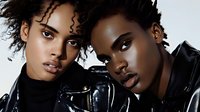 Young African American women with natural curly hair wearing black turtleneck and leather jacket posing together in artistic fashion portrait with dramatic lighting.