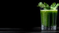Fresh green smoothie with celery in crystal glass on dark background, healthy detox drink for wellness and weight loss programs.