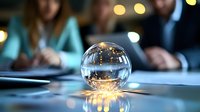 Crystal ball on business meeting table with blurred people in background and glowing bokeh lights reflecting through glass sphere for future prediction.
